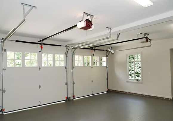 A garage interior with a garage door opener and an open garage door, showing a technician's workspace.