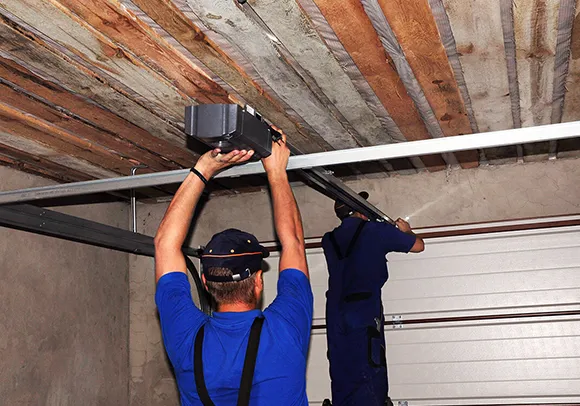 Two technicians repairing a garage door opener in a garage, showcasing expert repair services.