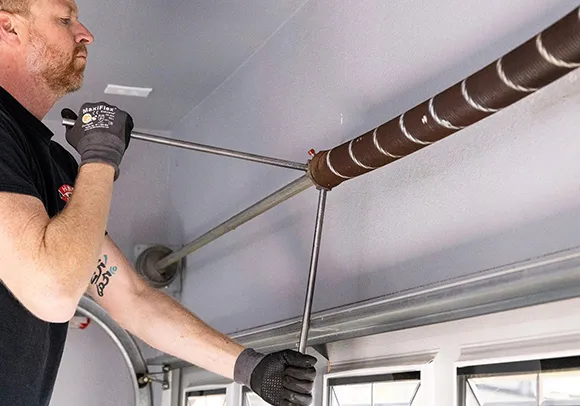 A technician working on a garage door torsion spring, demonstrating fast torsion spring replacement in Sacramento, CA.